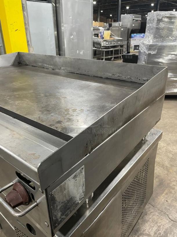 Wolf commercial stainless steel countertop flat griddle, natural gas powered, with back and side splash, on legs.