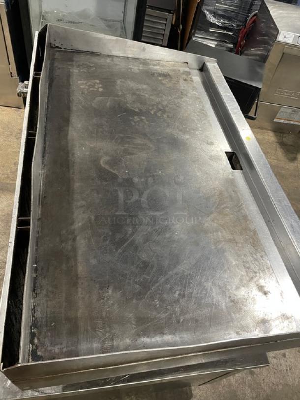 Wolf commercial stainless steel natural gas griddle with back and side splash, on legs. Shows signs of use.