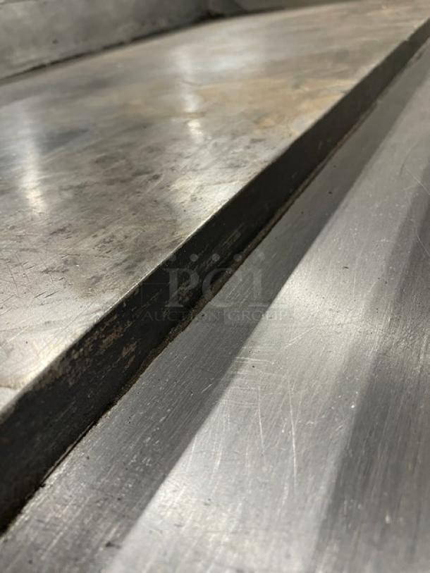 Wolf commercial stainless steel gas-powered countertop flat griddle with back and side splash, showing signs of wear.