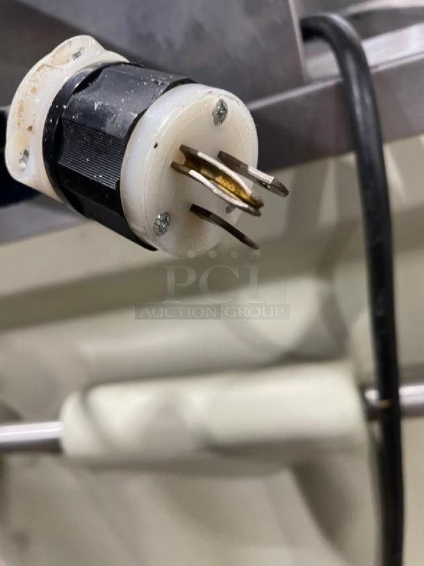 Close-up of electrical plug on a portable refrigerated cold food/salad bar. Stainless steel, with sneeze guard and folding tray slide.