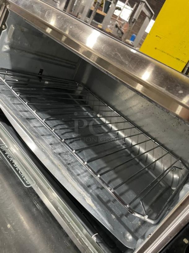 BLACK+DECKER TO3250XSB stainless steel convection toaster oven, extra wide, on legs, interior rack visible.