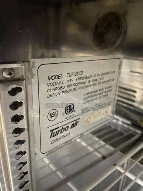 True TUF-28SD undercounter freezer, stainless steel, 115V, poly-coated wire rack, label shows technical specs, on casters.