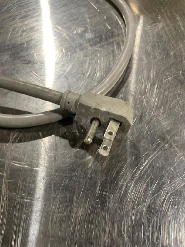 Power cord of True TUF-28SD undercounter freezer on stainless steel surface, 115V plug visible.