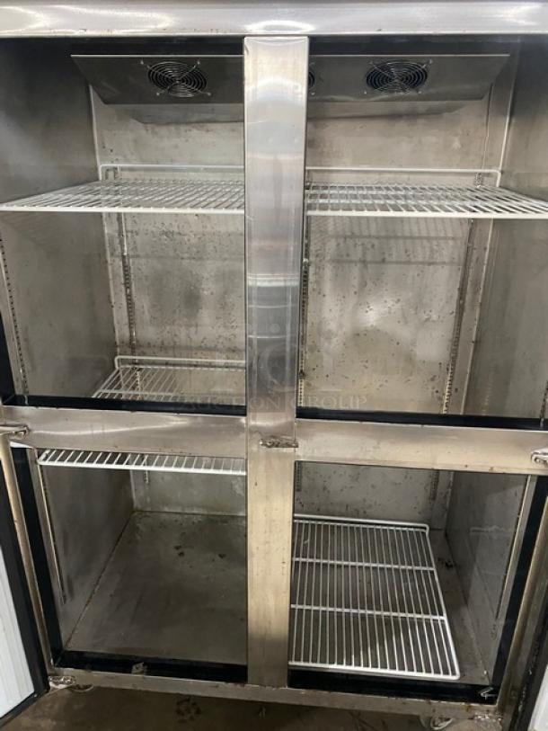 Commercial stainless steel double half-door refrigerator with poly-coated wire racks and casters. Visible wear inside.