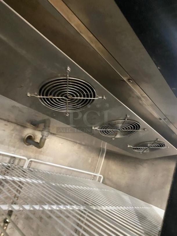 Commercial stainless steel double half-door reach-in refrigerator interior with poly-coated wire rack and ventilation fans.
