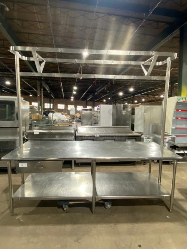 Commercial stainless steel worktop table with undershelf, overhead pots and pans rack, pull-out drawer, and sturdy legs.