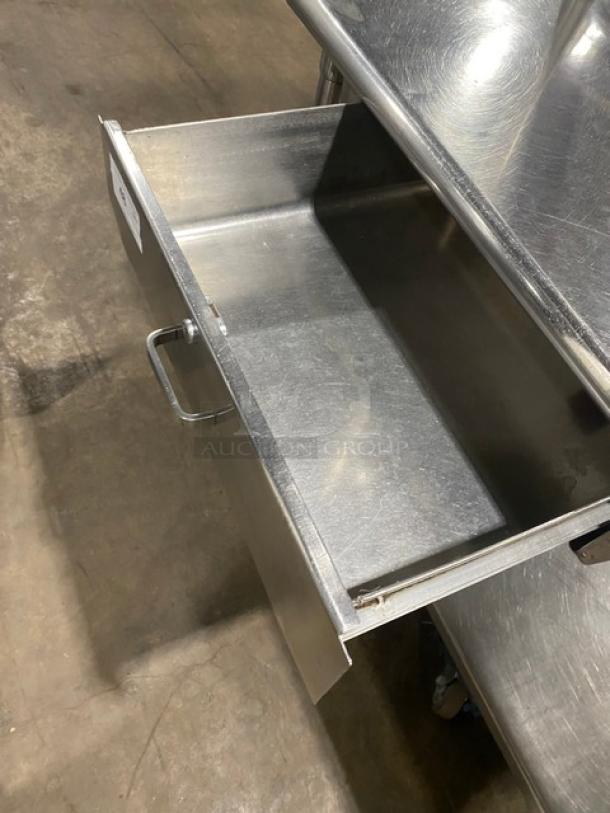 Commercial stainless steel worktop table with undershelf, overhead rack, and pull-out drawer. Features sturdy legs.