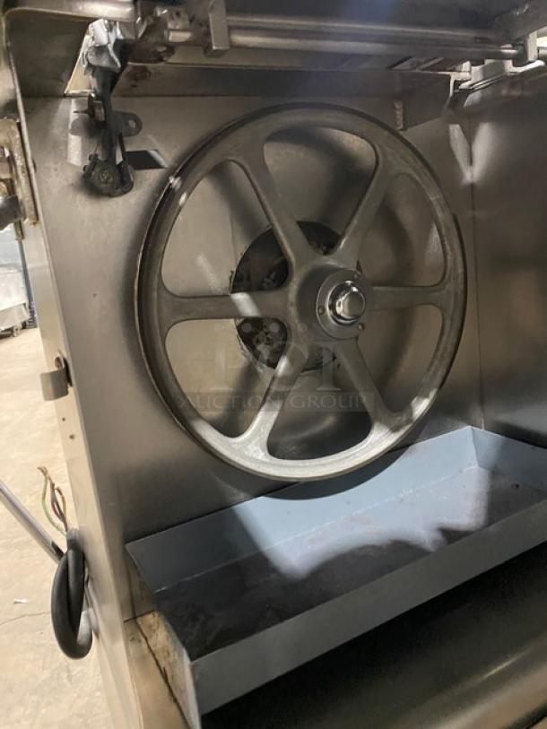 Butcher Boy stainless steel electric meat band saw, heavy-duty, free-standing on legs. Features robust wheel and blade housing.