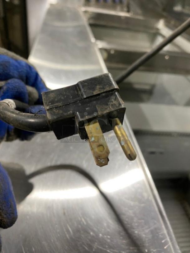 Close-up of a power plug for Randell Model 9040K7 refrigerated prep table, showing standard prongs and black casing.