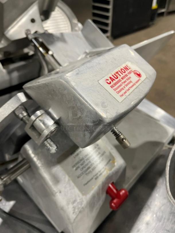 Fleetwood commercial electric meat deli slicer; heavy-duty countertop model, on legs. Visible caution label; metal finish.