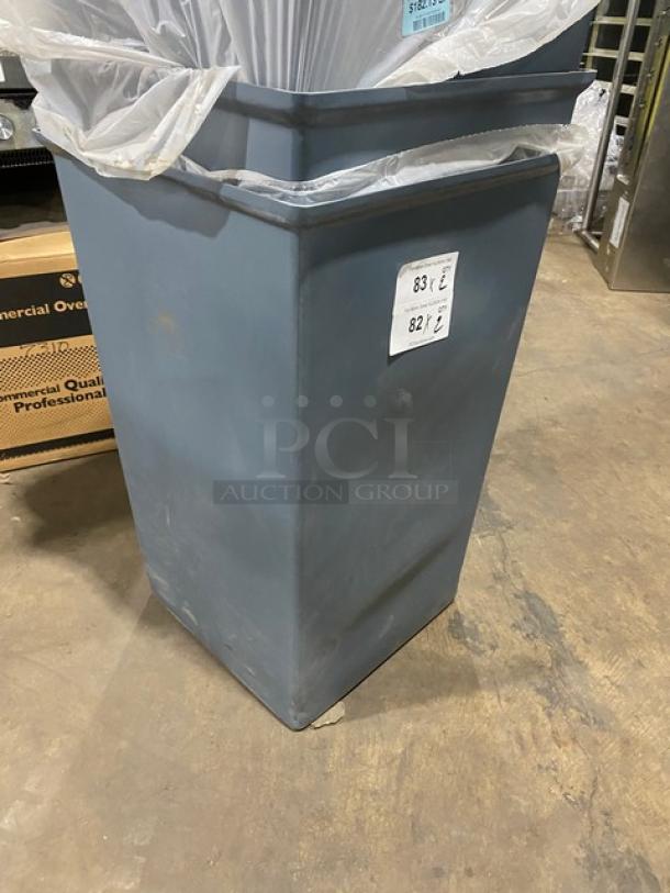 Large gray commercial square trash can, good condition, includes plastic liners. Auction labels 83 and 82 visible.