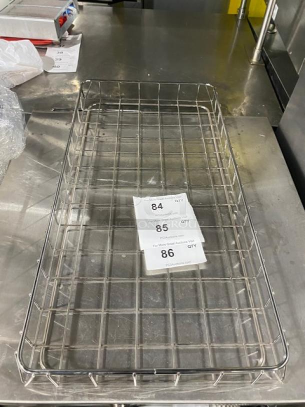 Commercial chrome-plated full-sized bagel/pastry wired rack on metal surface. Features grid design. Labels with lot numbers visible.
