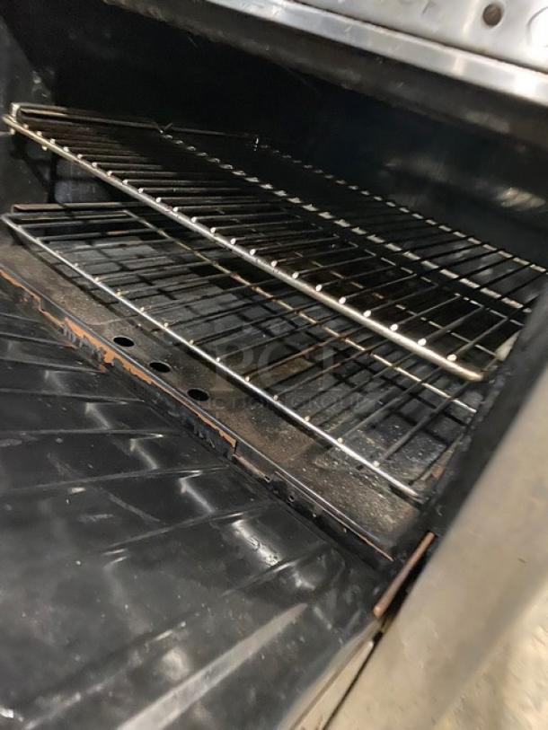 Garland commercial stainless steel oven interior with wired rack, part of a 2-burner/flat plate range and overhead broiler combo.