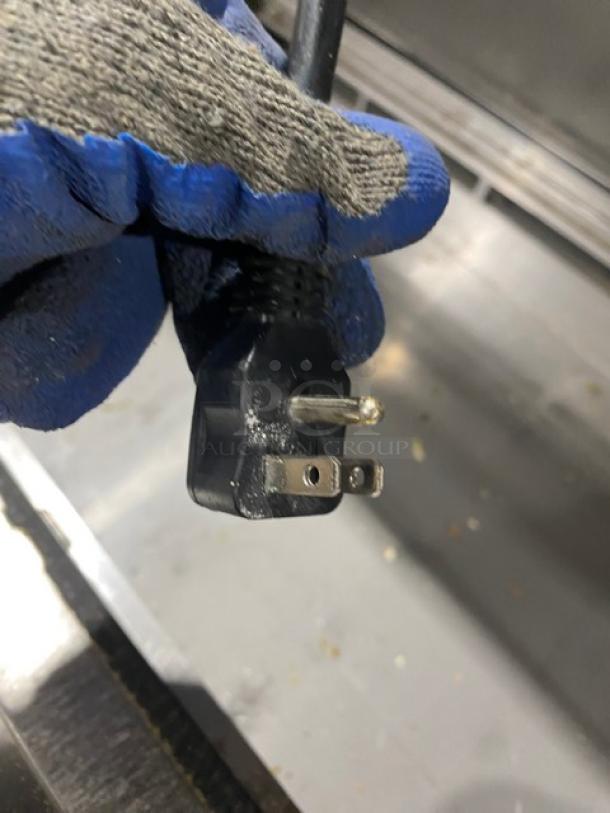Close-up of a power plug held by a gloved hand.