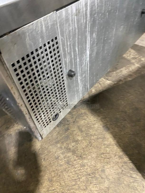 Commercial stainless steel 2-drawer refrigerated chef base with visible casters, showing wear, lattice panel detail.