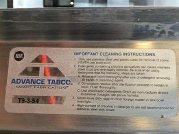 Advance Tabco T9-3-54 three-compartment stainless steel sink, NSF certified. "Smart Fabrication" label with cleaning instructions visible.