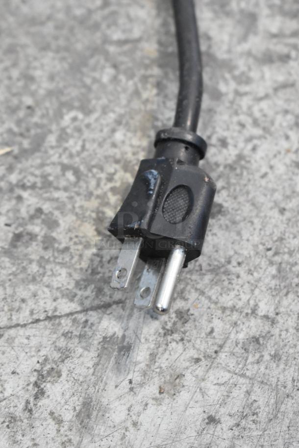 Close-up image of a black power plug with two metal prongs and a grounding pin, suitable for 115 volts, 1 phase connections.