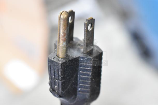 Close-up of a three-prong electrical plug with visible wear.