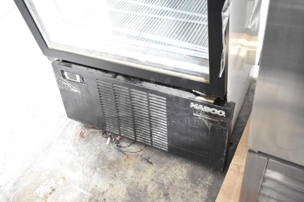 Habco SF28M commercial freezer with single glass door, poly-coated racks. Visible wear on exterior. Model tag shows 115V, 1-phase.