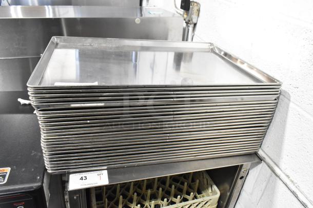 24 metal full-size baking pans stacked, clean condition, suitable for commercial kitchens. Auction lot number 43.