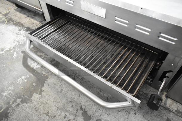 Standard Range stainless steel commercial cheese melter, features a pull-out rack, in used condition with visible grill marks.
