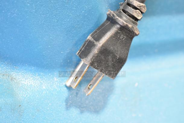 Close-up of a black power plug on a Servend SV150 carbonated beverage machine, against a blue surface.
