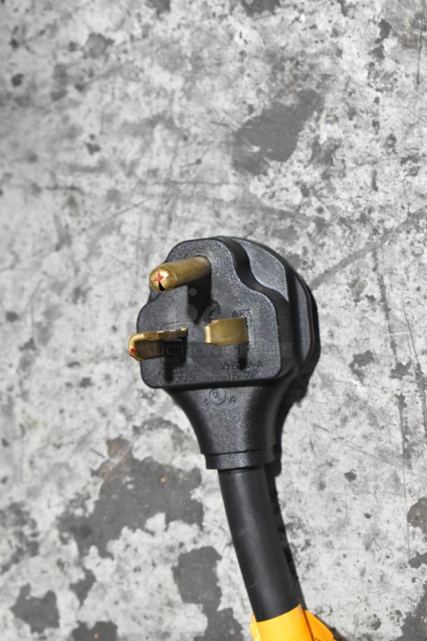 Black plug of a Paragon TP-16 popcorn machine, featuring three gold prongs on a textured surface.