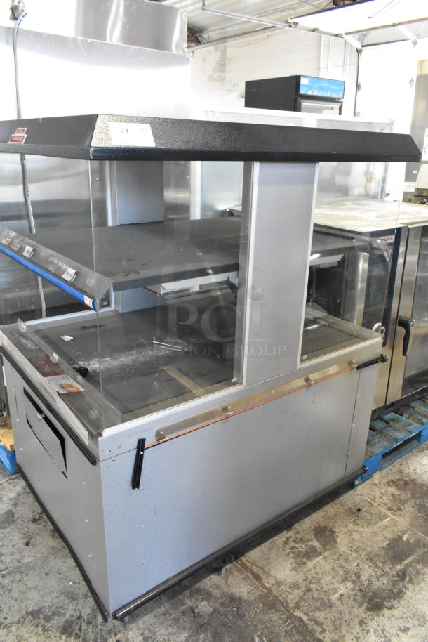 Custom Deli's 2-tier metal warming display merchandiser with glass panels, on commercial casters, in used condition.