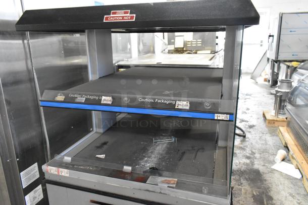 Custom Deli's 2-tier metal warming display merchandiser on casters; shows caution labels; used condition.
