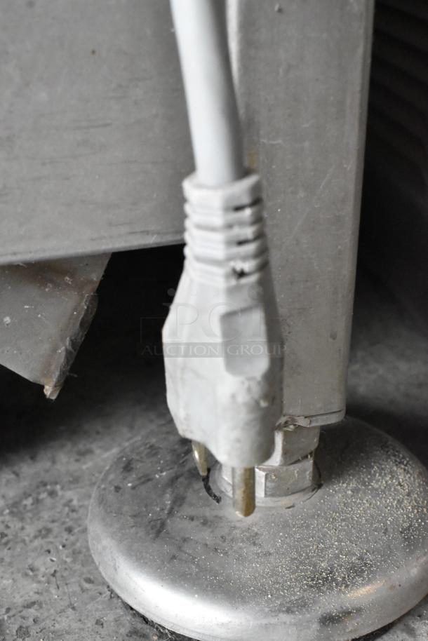Bizerba metal commercial meat slicer plug on stainless steel stand. 115 volts, 1 phase. Close-up of power cord connection.