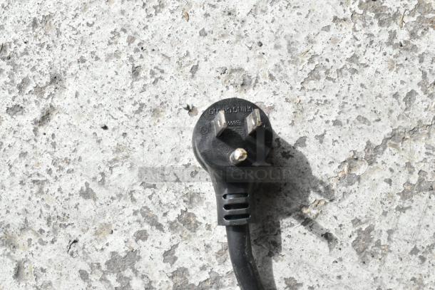 Alt text: Close-up of a black electrical plug on a textured concrete surface.