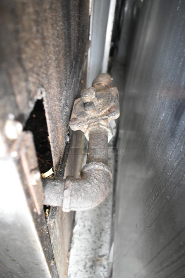Rusty gas pipe section of a Tri-Star stainless steel commercial 4-burner range. Pipes show signs of use and corrosion.