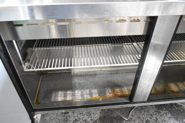 Turbo Air MST-60-24 metal sandwich prep table, showing interior wire shelves, visible wear, and commercial casters.