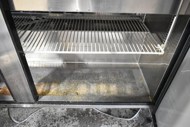 Turbo Air MST-60-24 commercial prep table interior, metal shelves, visible wear, debris on lower shelf, 115V, 1 phase.
