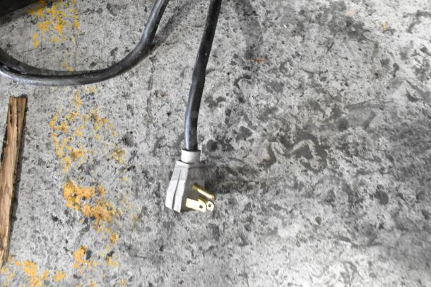 Power cord of True GDM-41SL-54EM-LD reach-in cooler on concrete floor.