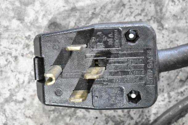 Close-up of a heavy-duty power plug from a Fri-jado TDR7-P rotisserie oven, showing prongs and voltage markings.