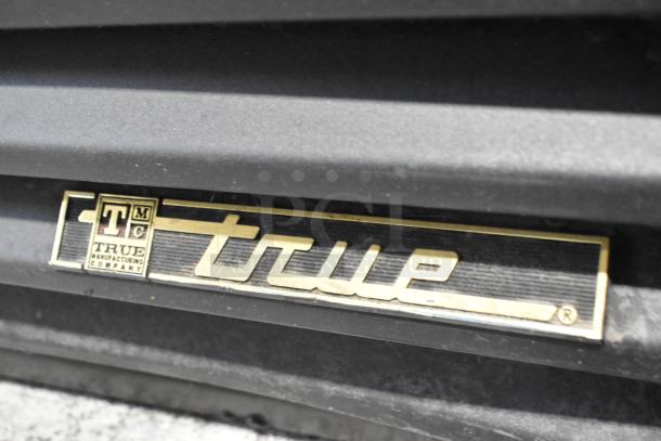 True GDM-41SL-60-LD metal cooler merchandiser badge, black and gold design, indicating the manufacturer.