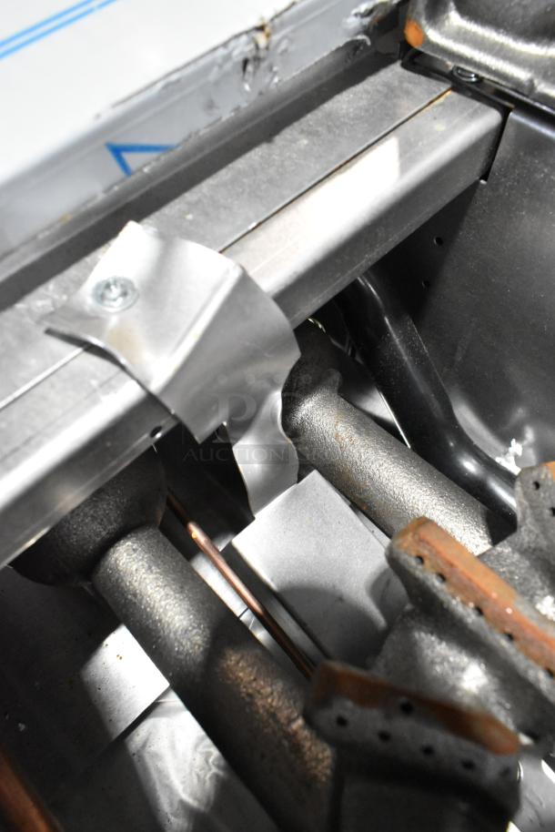 Close-up of burners on Garland 372G366CN commercial natural gas range. Stainless steel construction. Visible connectors.