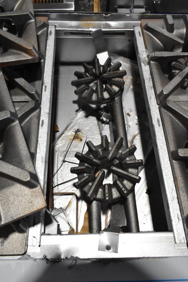 Brand new Garland 372G366CN stainless steel commercial range, showing burners, slight scratch and dent condition.