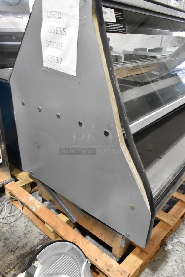 Custom Deli's metal commercial floor warming display case, visible glass shelves, "Used Assets Store" tag, minor wear.