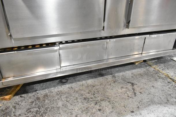 Champion Tuff 782TG60 stainless steel 60" wood burning grill, showing sturdy construction, minor wear, and storage compartments.