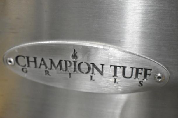 Brand new Champion Tuff 782TG60 wood-burning grill. Stainless steel with visible logo plate. Scratch and dent condition.