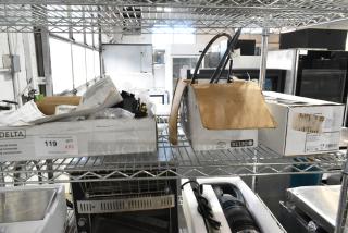 Three brand new Delta Faucet models, in boxes on a shelf, with packaging and labels visible, featuring touchless and lever technologies.