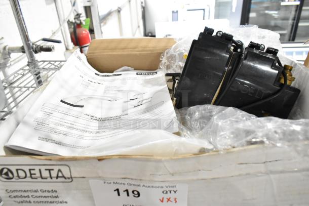 Box of three new Delta faucets, including touchless models and stainless finish, with installation instructions and packaging.