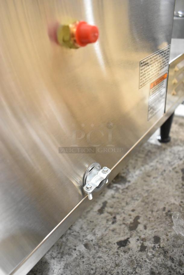 Stainless steel panel of Bunn AXIOM 0/6 TWIN coffee brewer showing warning label and fittings.