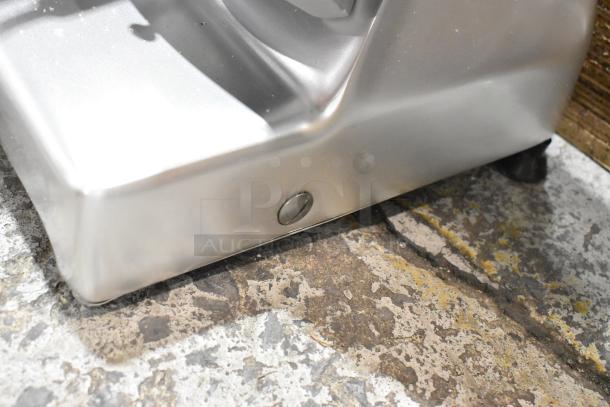 Bottom corner of Globe G10 slicer base, showing a minor scratch, on a concrete floor.
