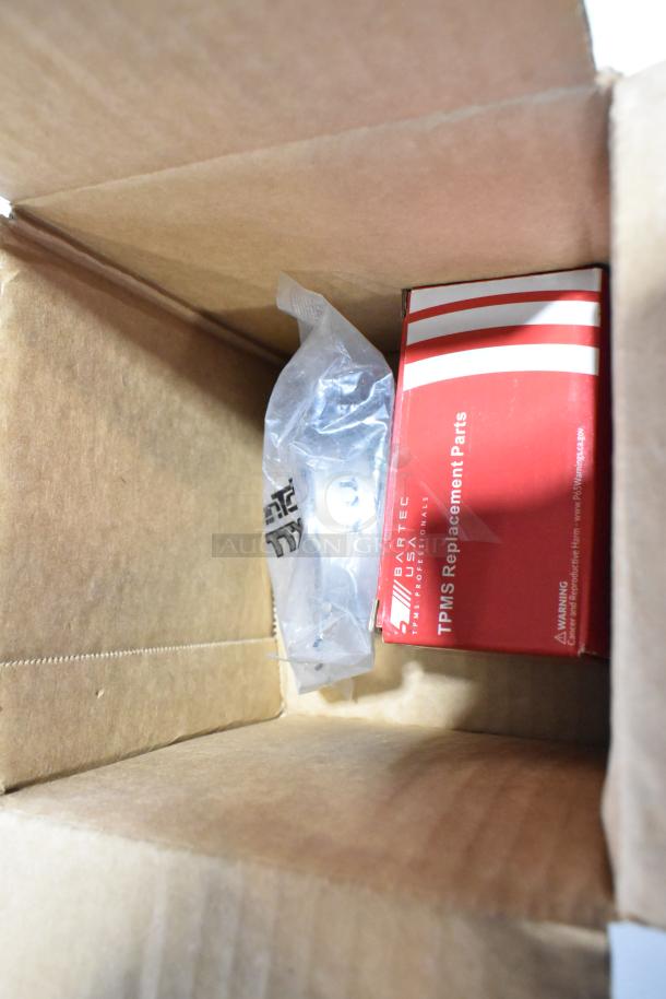 Cardboard box containing a red box labeled "Bartec TPMS Replacement Parts" and a sealed plastic bag. Scratch-and-dent items inside.