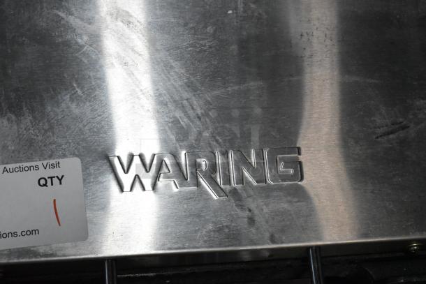 Waring WDG250 stainless steel panini press with embossed brand logo. Commercial-grade, 120V, 1 Phase. Slight wear visible.