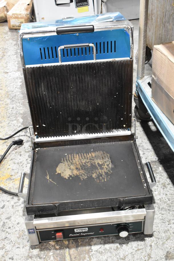 Waring WDG250 stainless steel commercial panini press, 120V, shows signs of wear; features non-stick plates, model markings visible.
