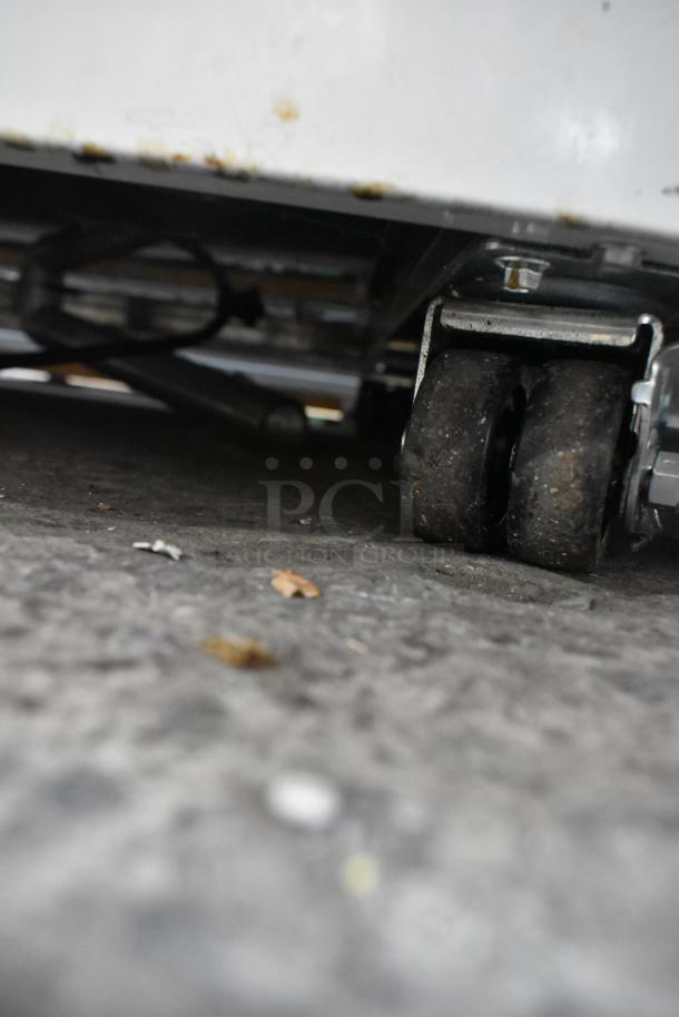 Metal commercial freezer on heavy-duty casters, 115 volts, 1 phase. Visible undercarriage detail. Good working condition.